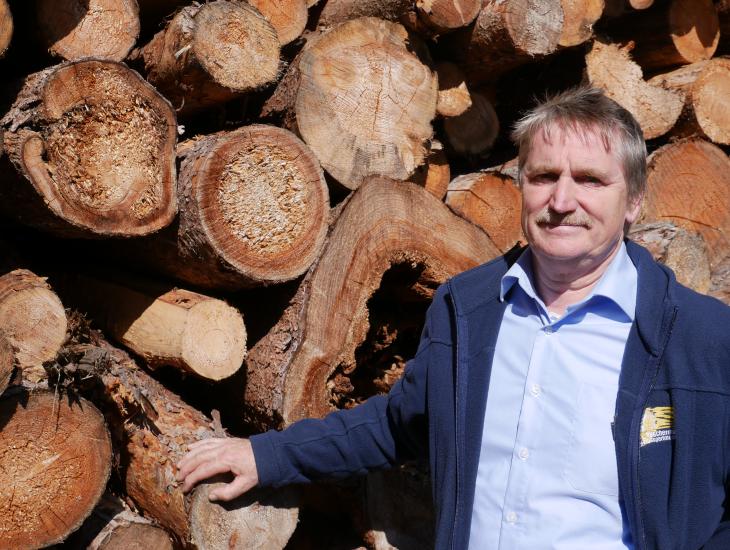 Wolfgang Degelmann vor Holzstapel