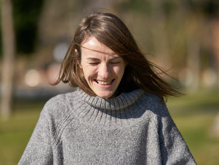 Eine junge Frau lacht mit geschlossenen Augen.